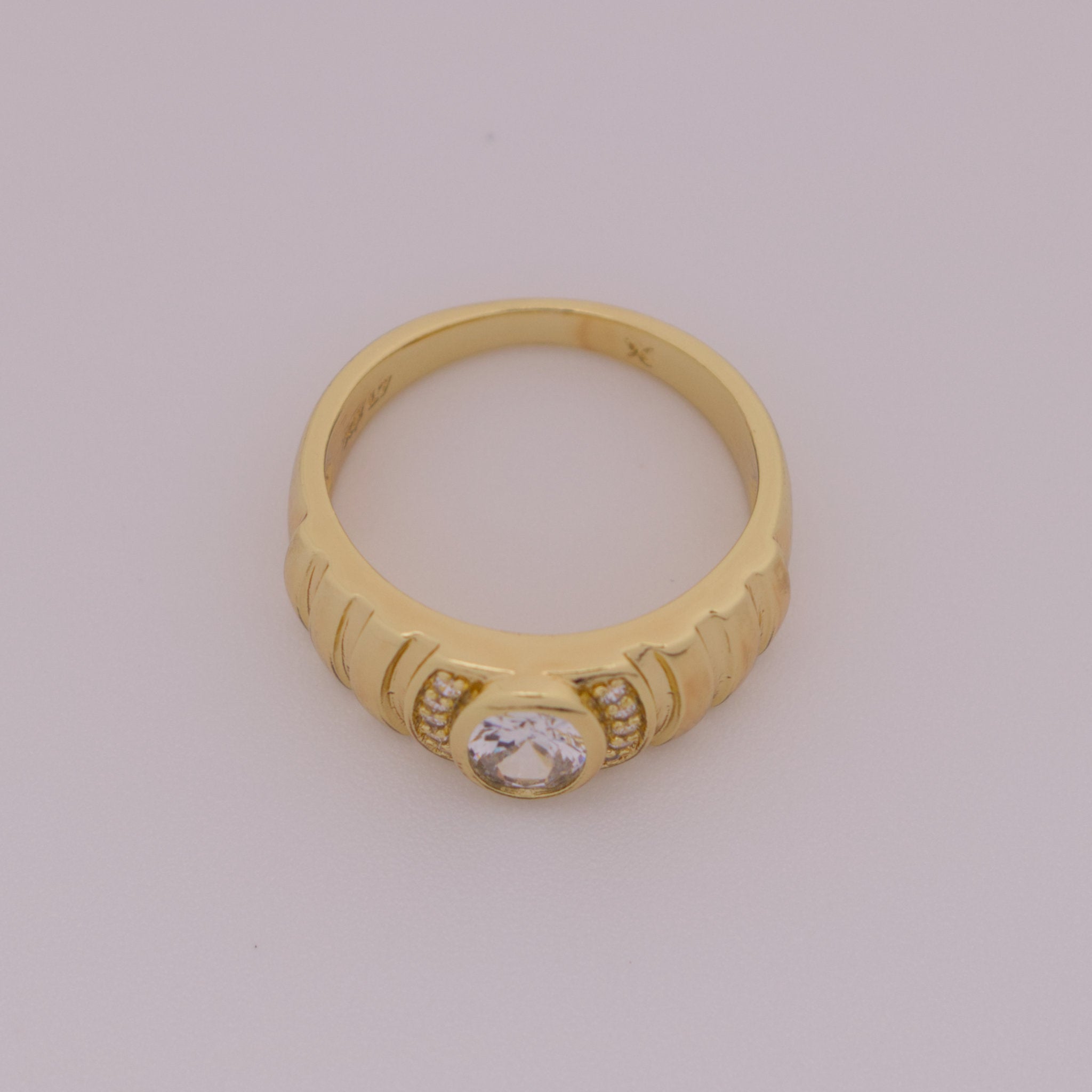 Gold ring with a diamond on a light gray background