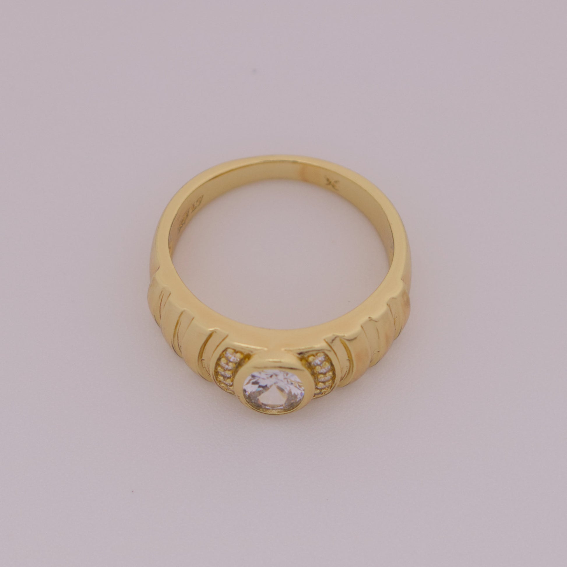 Gold ring with a diamond on a light gray background