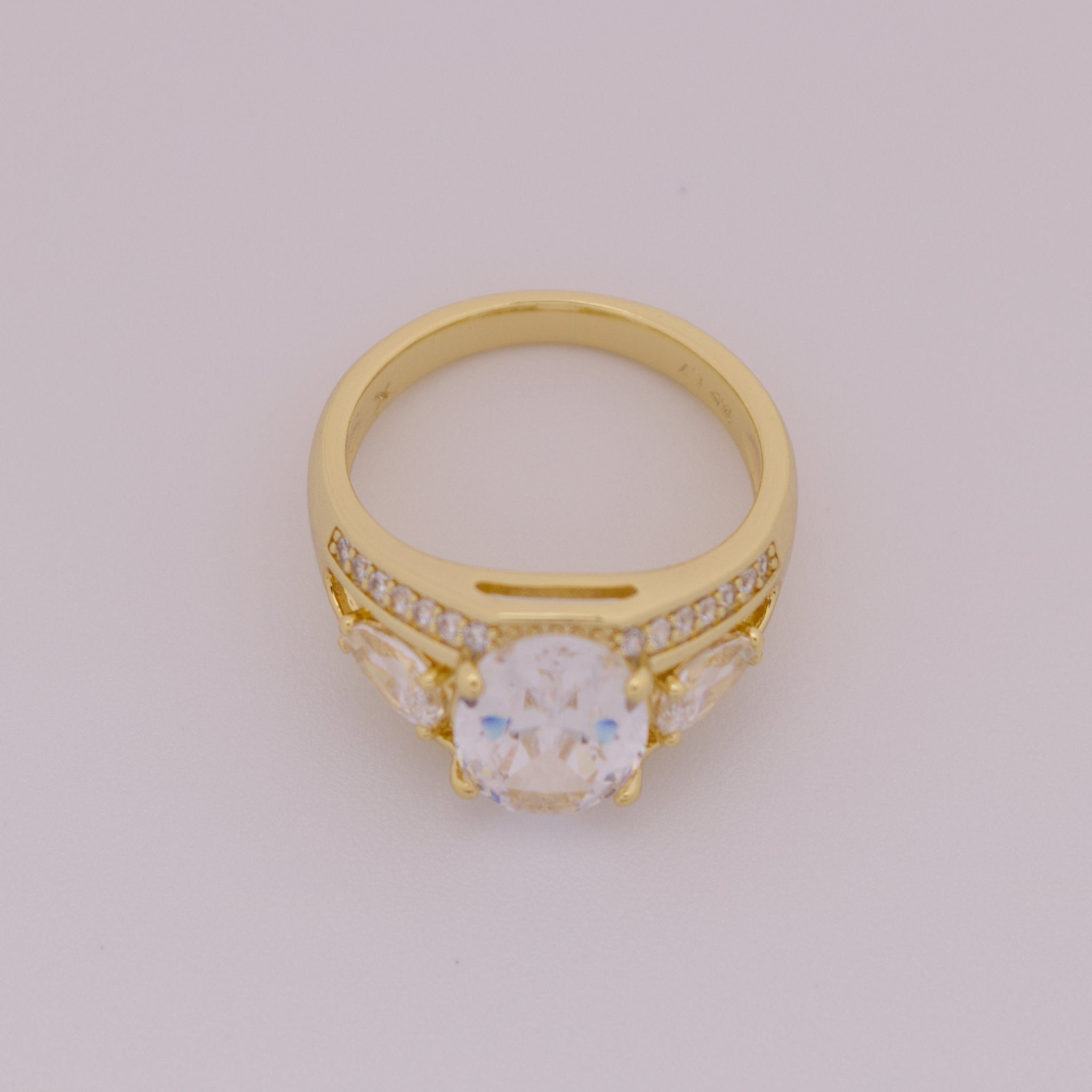 Gold ring with a central gemstone and smaller stones on a light gray background