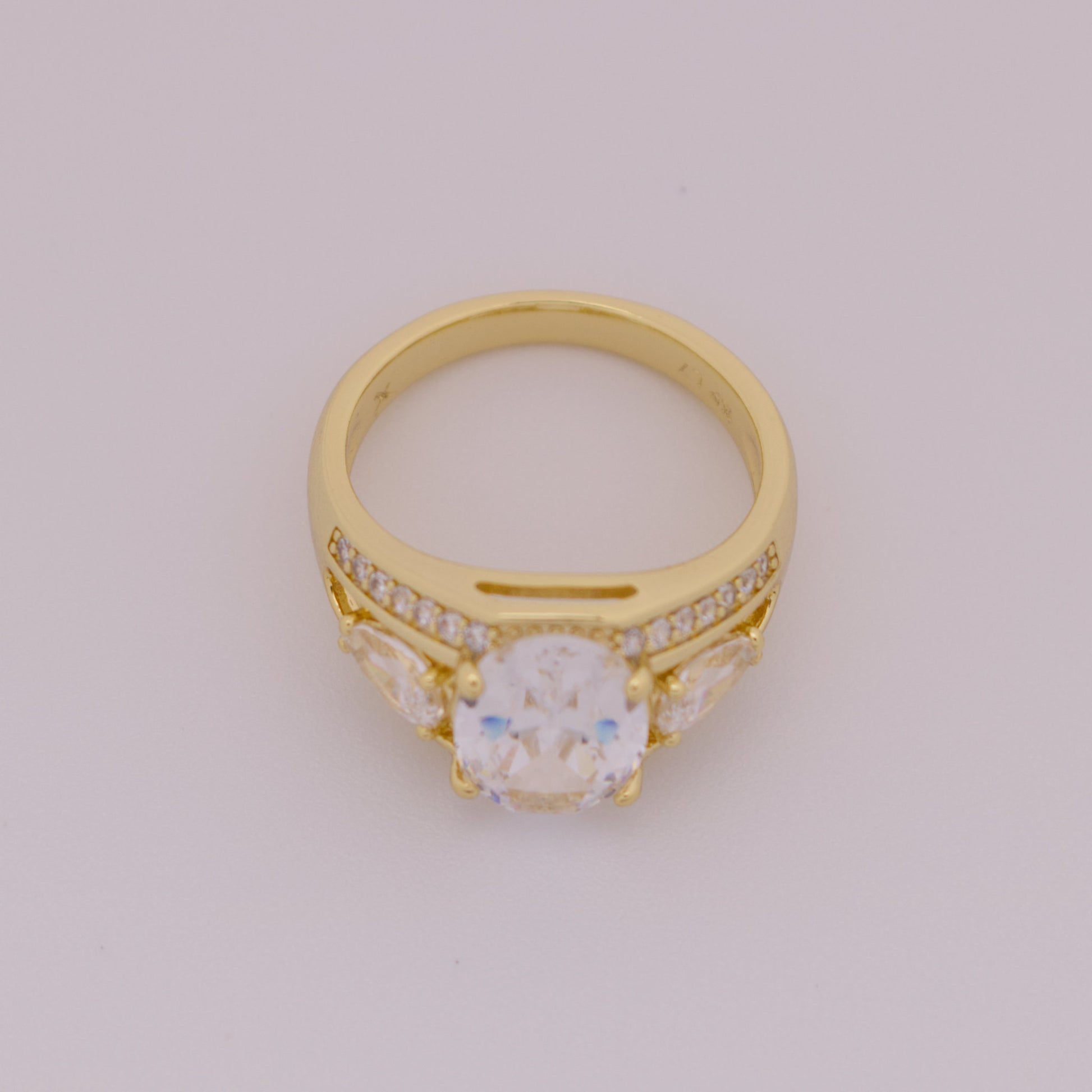 Gold ring with a central gemstone and smaller stones on a light gray background