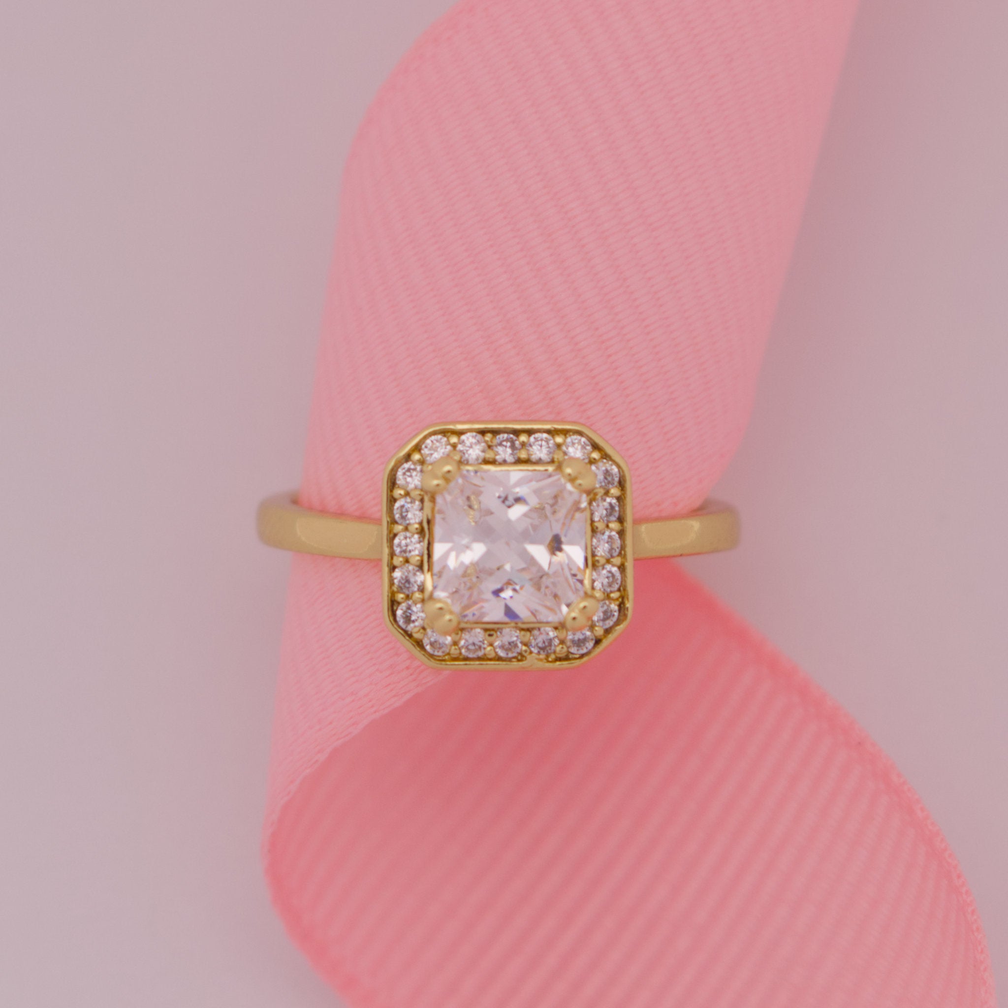 Gold ring with a large diamond on a pink ribbon