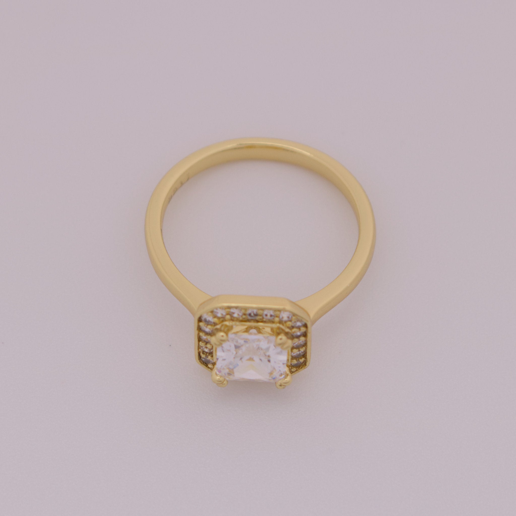 Gold ring with a diamond on a light gray background