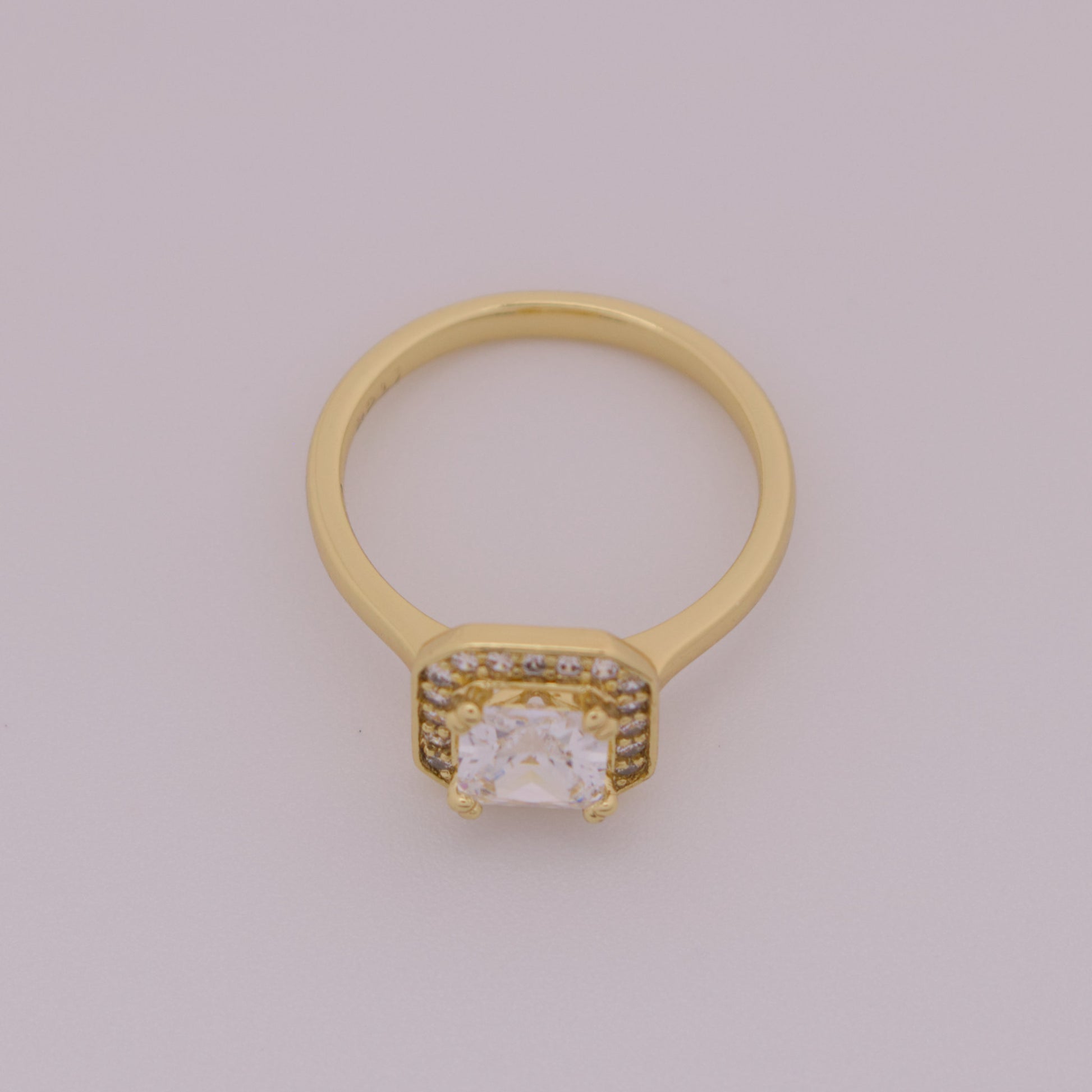 Gold ring with a diamond on a light gray background