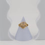 Gold ring on a gray cone-shaped stand against a light gray background