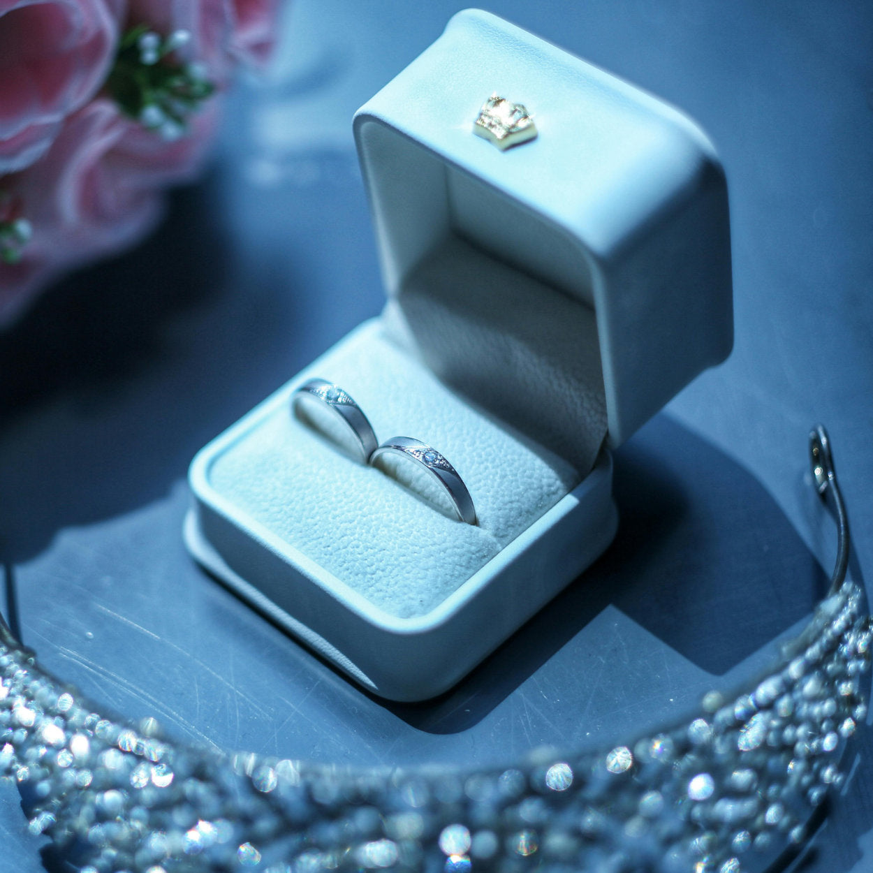 Silver ring in an open jewelry box on a reflective surface with blurred background