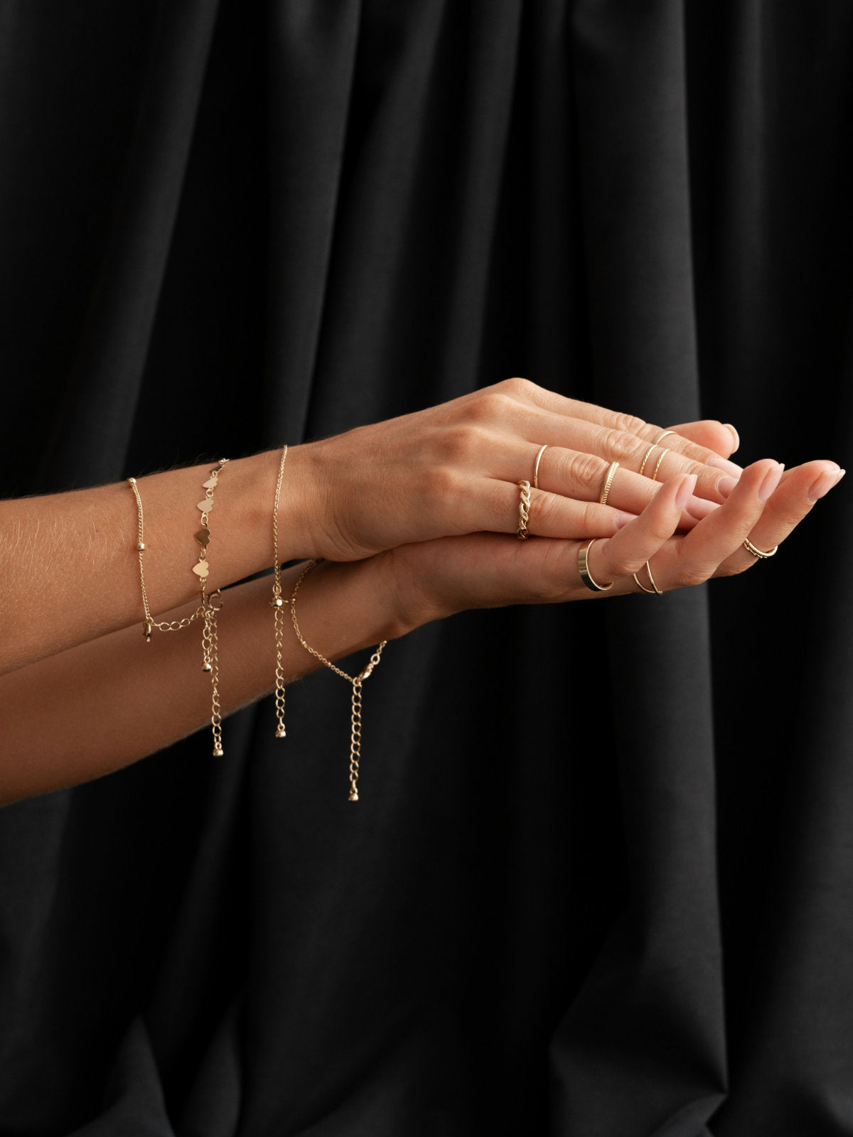 Gold jewelry including bracelets and rings on a black background