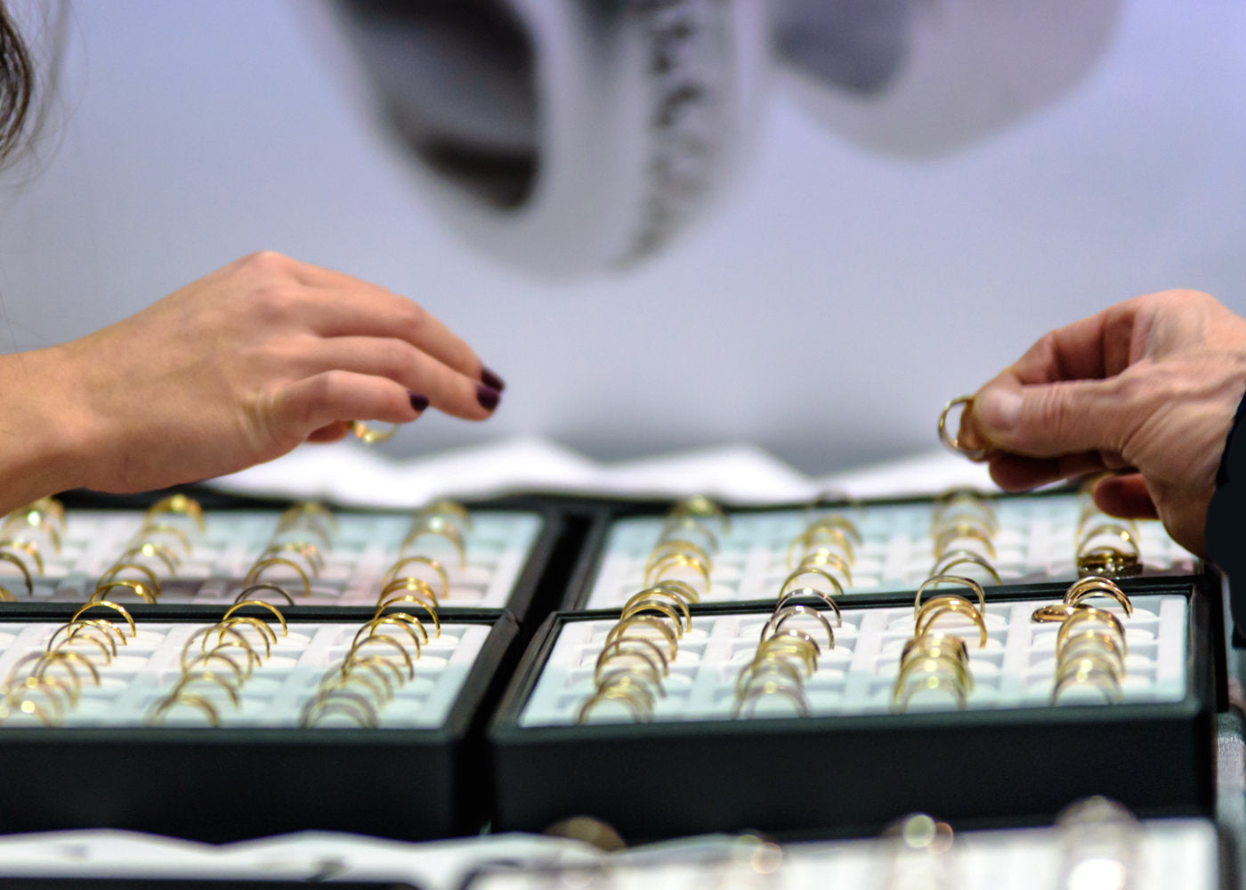 Person examining gold earrings in a display case