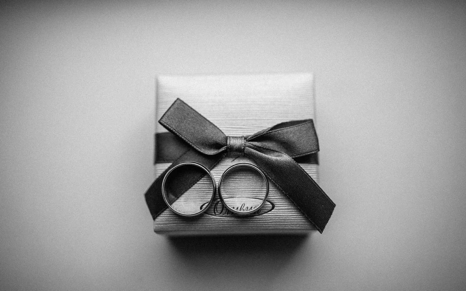 Two rings on a gift box with a bow on a gray background