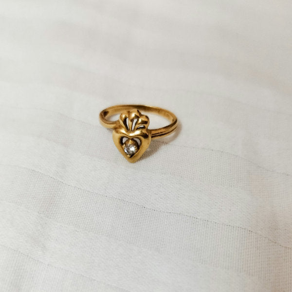 Gold ring with a heart design on a white fabric background