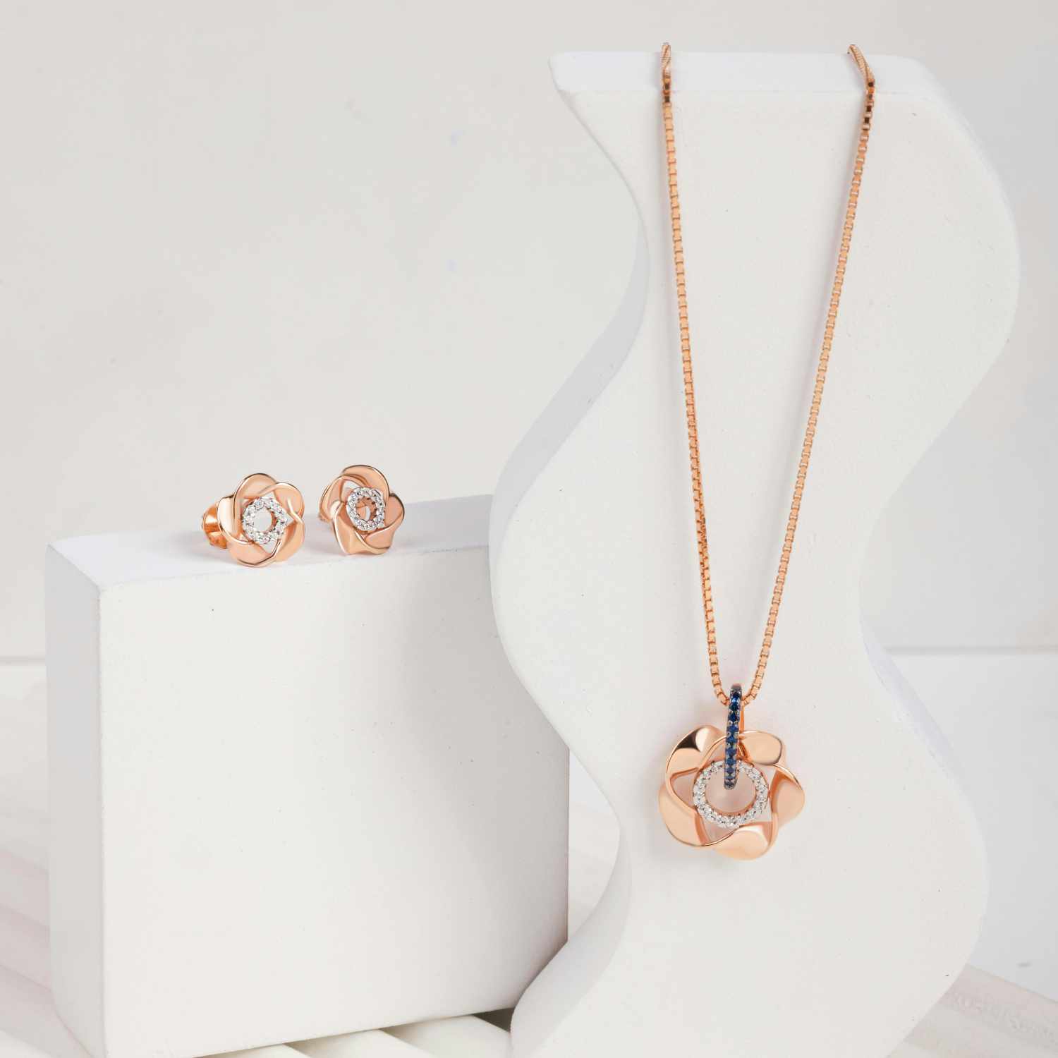 Rose gold jewelry set with necklace and earrings on a white background