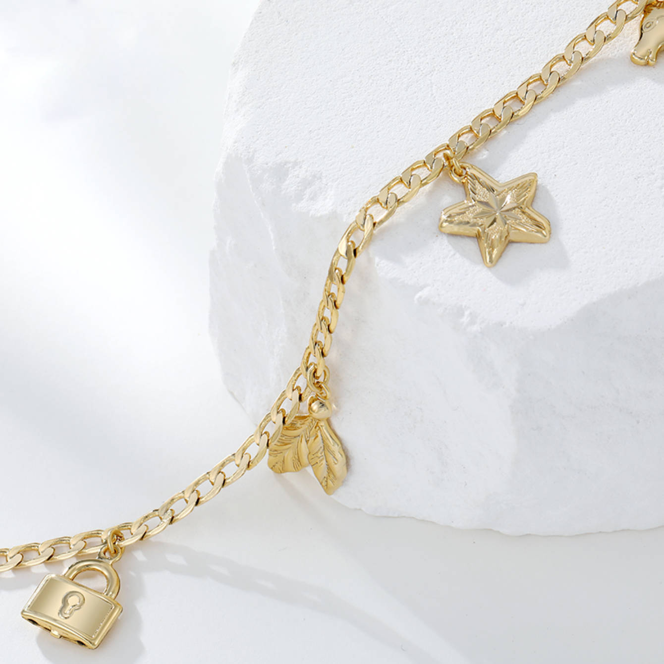 Gold bracelet with star and padlock charms on a white background