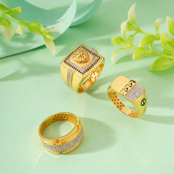 Three gold rings with diamond accents on a light green background