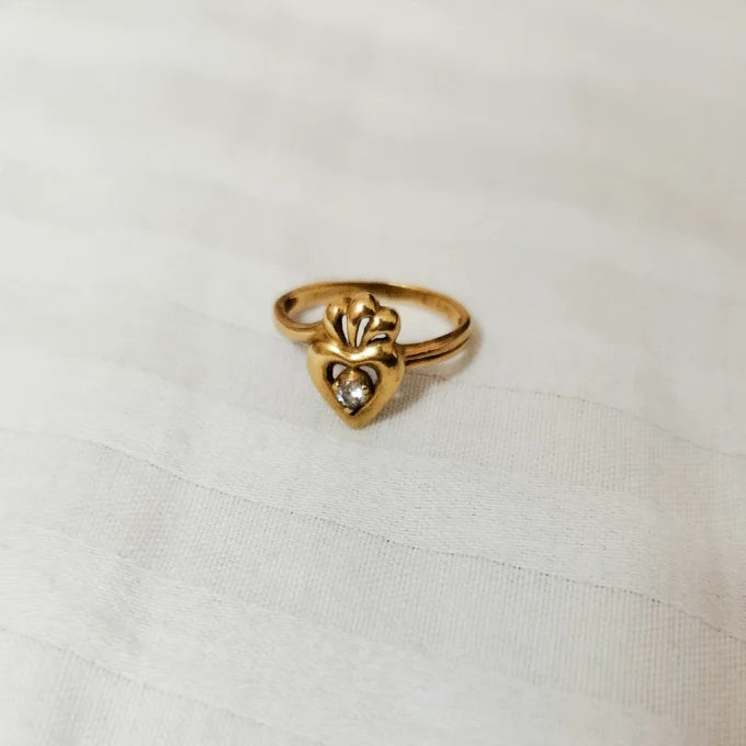 Gold ring with a heart design on a white fabric background